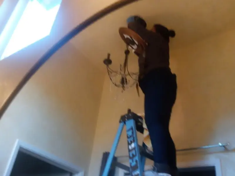 Electrician installing a chandelier in a Hartville residence